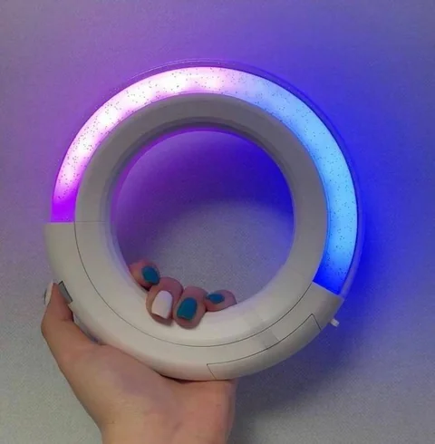 Anneau lumineux ITZY tenu à la main, éclairé en violet et bleu
